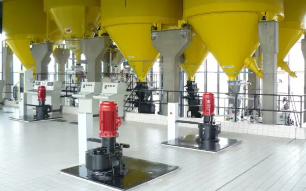 Ruimte met hangende gele silo's en 3 pompen op de voorgrond